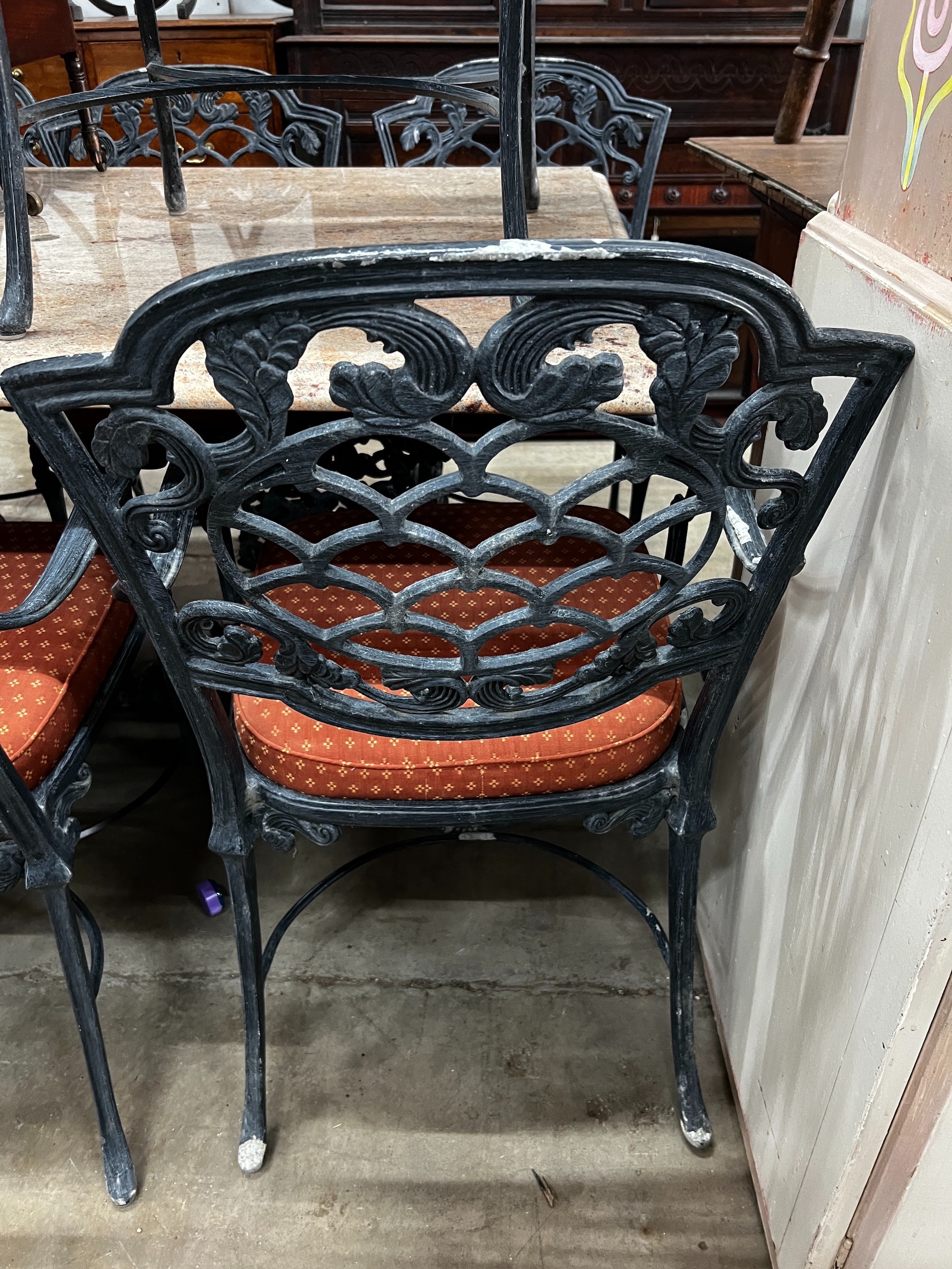 A rectangular cast metal marble topped garden table, length 140cm, depth 100cm, height 75cm and eight chairs with drop in seat pads (2 with arms)